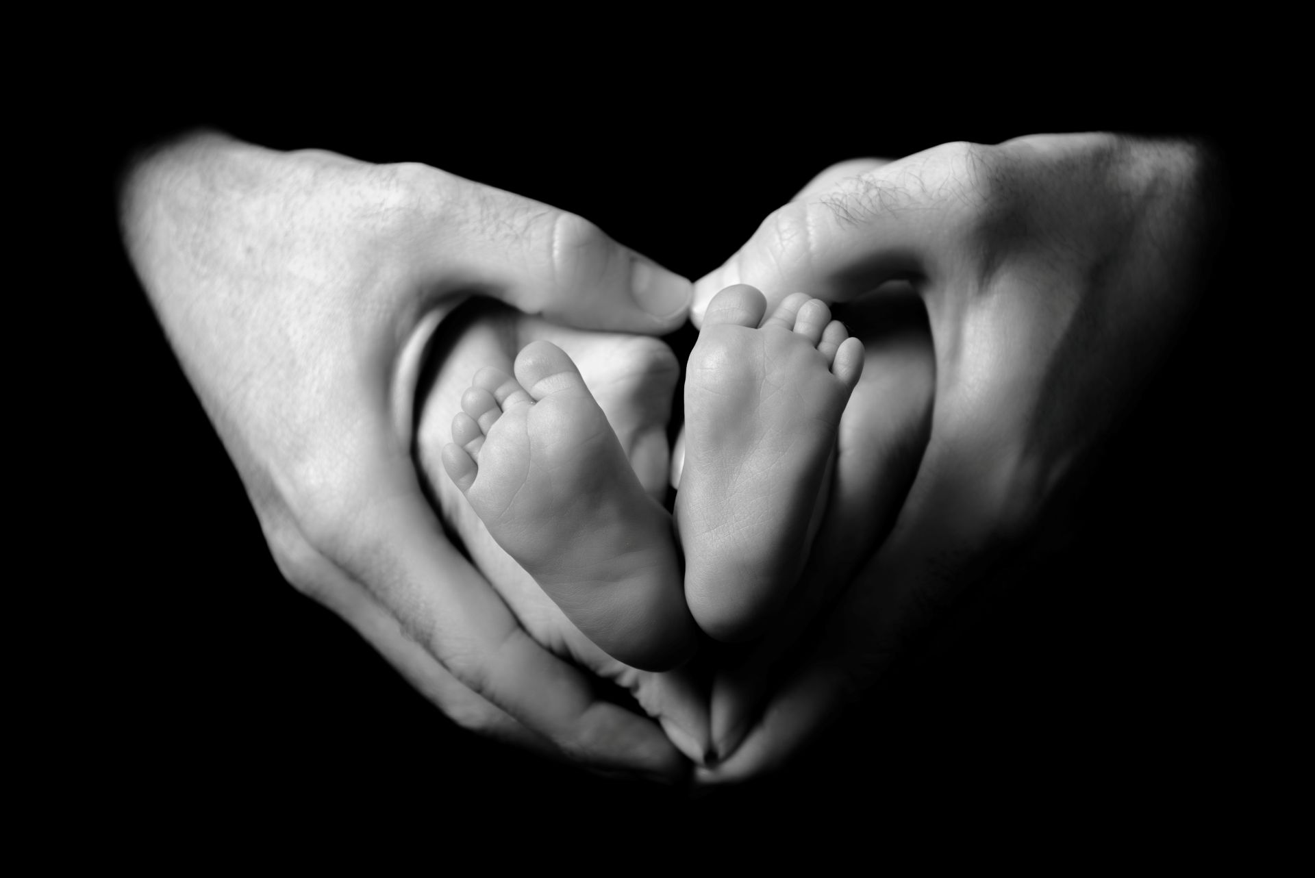 Détail des pieds d'un bébé tenus dans les mains