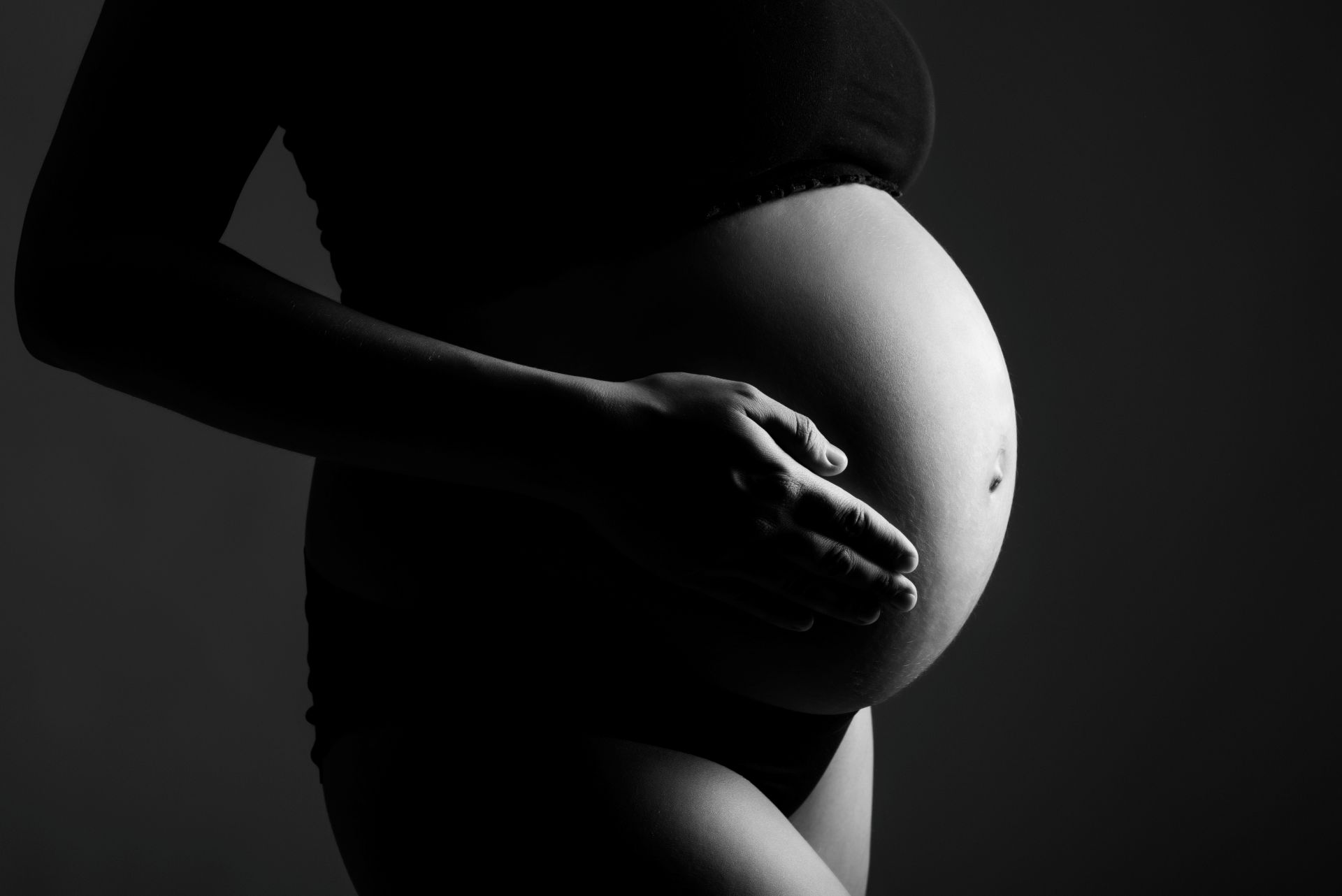 Détail d'un ventre de grossesse en clair-obscur